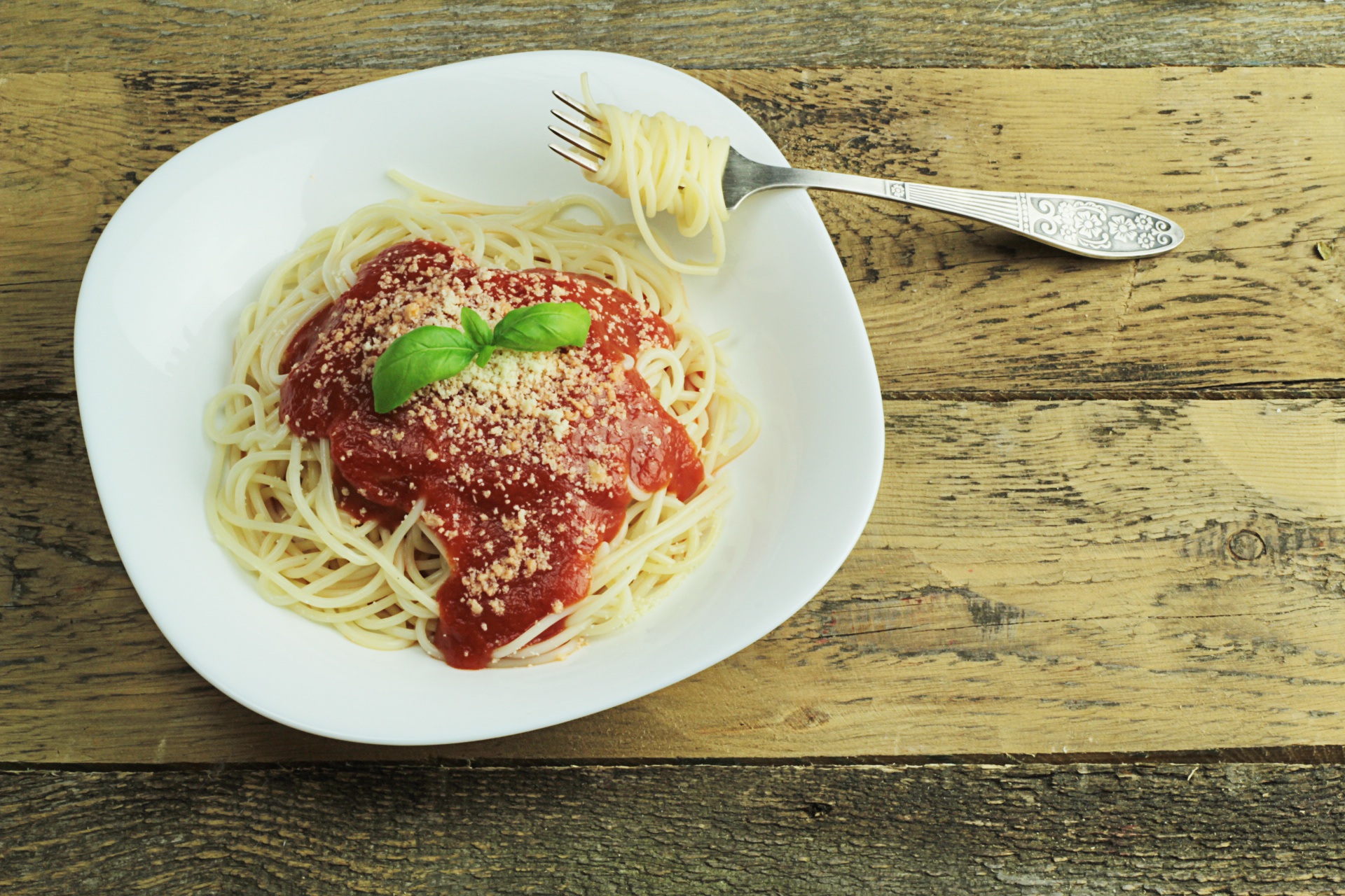 Foto de um saboroso macarrão spaguetti com molho de tomate, queijo ralado e manjericão